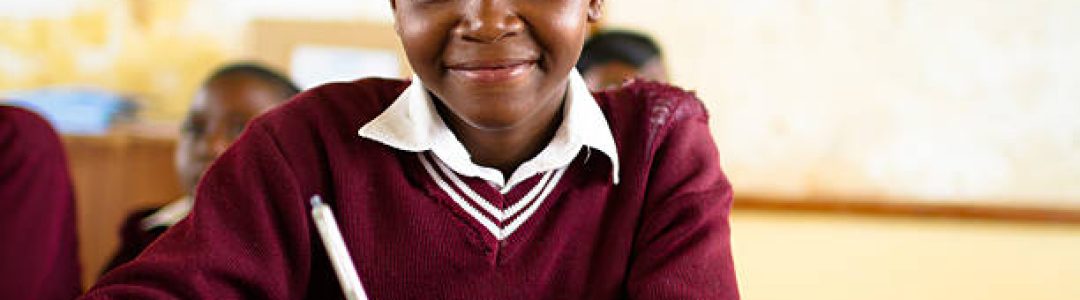 South African girl (from the Xhosa tribe) works on her studies at an old worn desk in a class room in the Transkei region of rural South Africa.